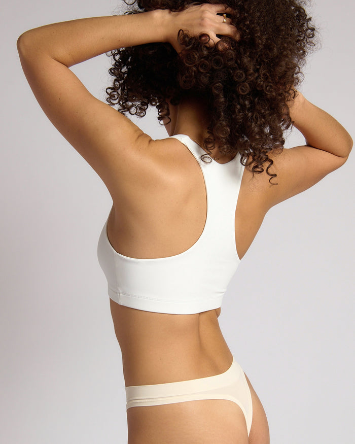 Woman wearing a white racerback on a plain background