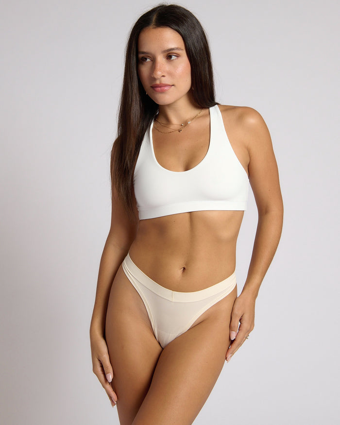 Woman wearing a white racerback on a plain background