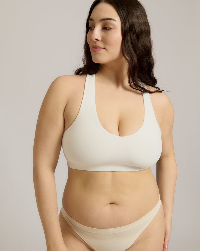 Woman wearing a white racerback on a plain background
