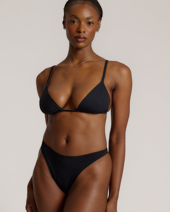 Black triangle bra worn by a model on a plain background