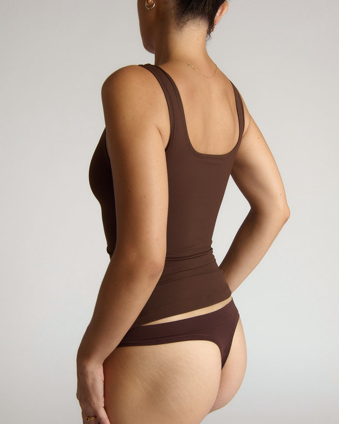 Woman wearing a brown tank top against a plain background