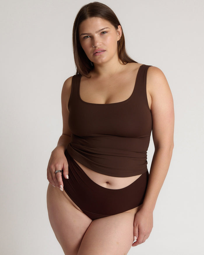 Woman wearing a brown tank top against a plain background