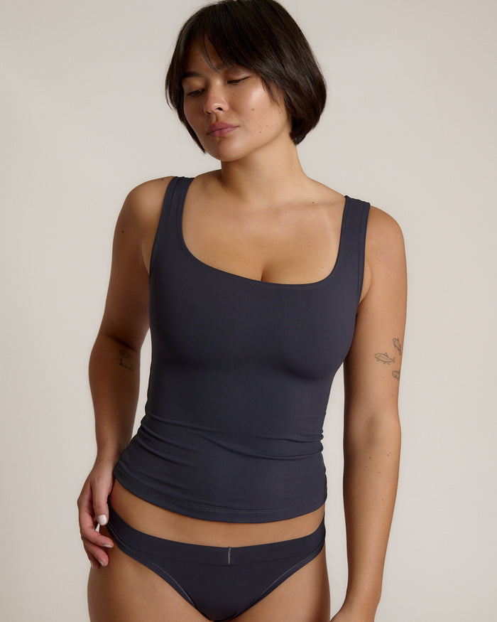 A woman modeling a myst scoop-neck tank top and a matching thong against a plain light gray studio background.