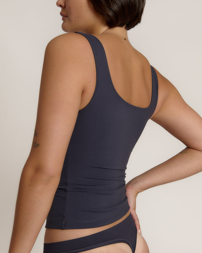 A woman modeling a myst scoop-neck tank top and a matching thong against a plain light gray studio background.