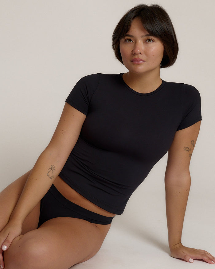 Woman wearing a black t-shirt against a plain background