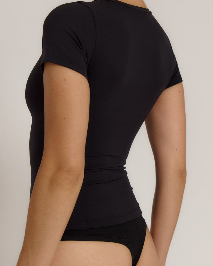 Woman wearing a black t-shirt against a plain background