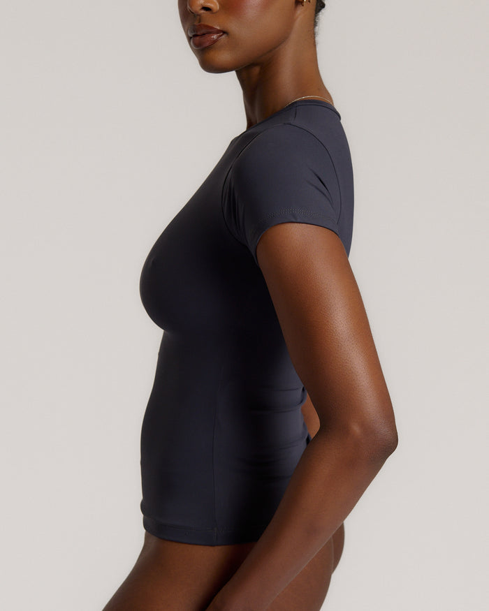 A woman modeling a myst tee and a matching thong against a plain light gray studio background.