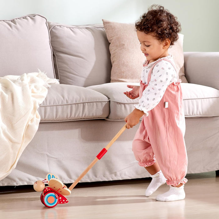 Child playing with the butterfly push toy in a living room