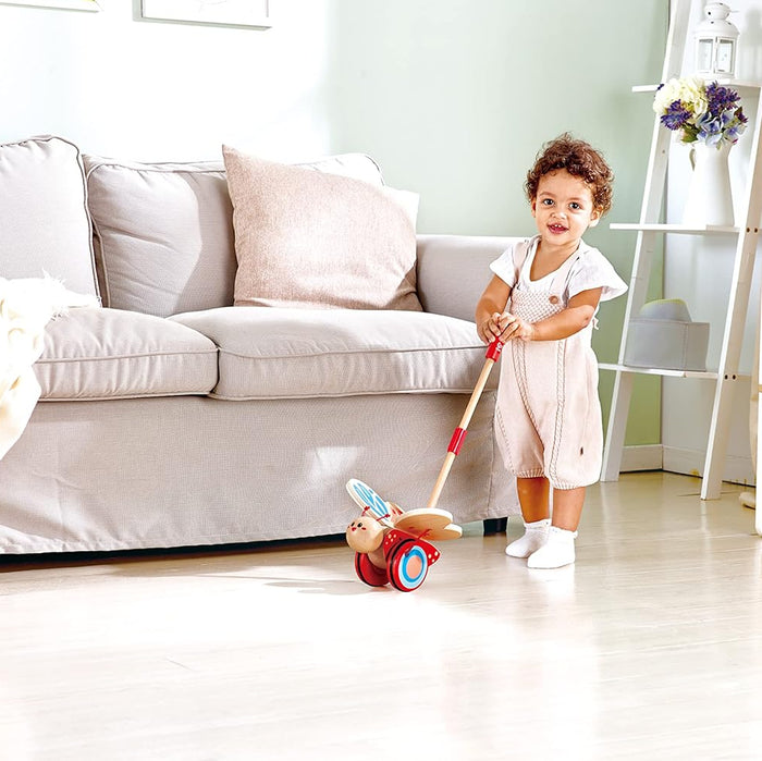 Child playing with the butterfly push toy in a living room