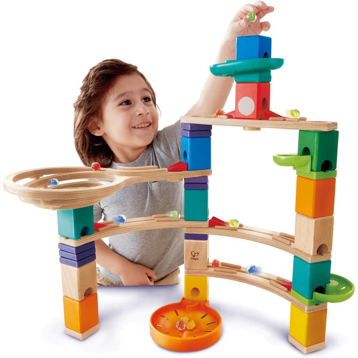 Child playing with a colorful marble run toy set on a white background