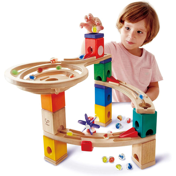 Child playing with a colorful marble run toy set on a white background