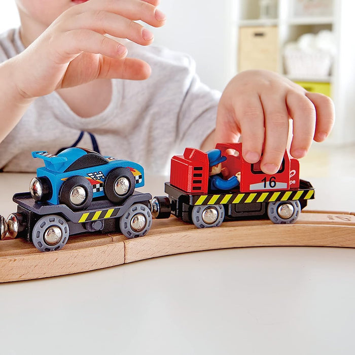 Child playing with toy and a blue race car  on a wooden track