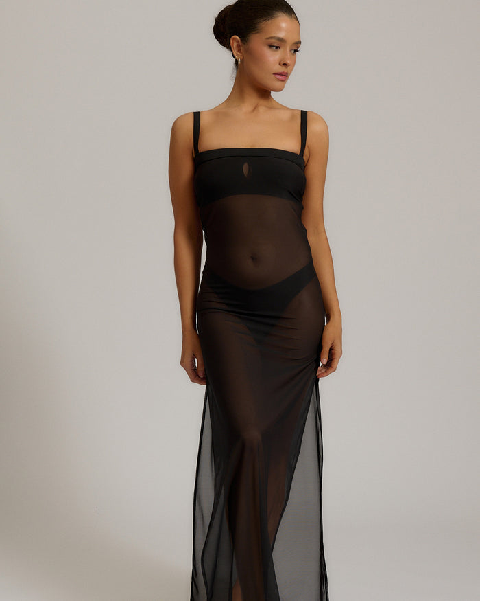 Woman wearing a black sheer dress against a plain background