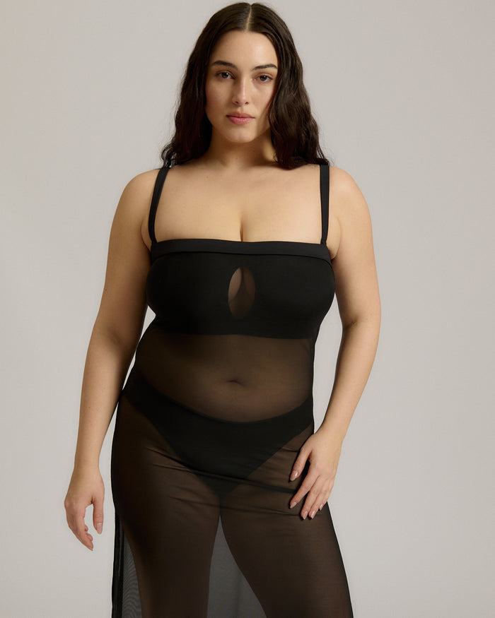 Woman wearing a black sheer dress against a plain background