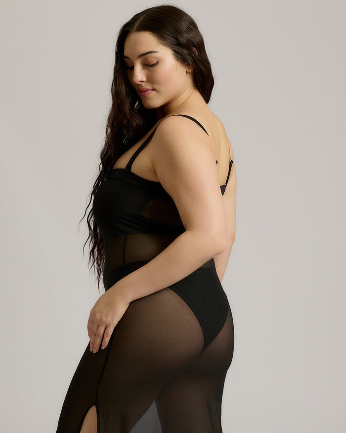 Woman wearing a black sheer dress against a plain background