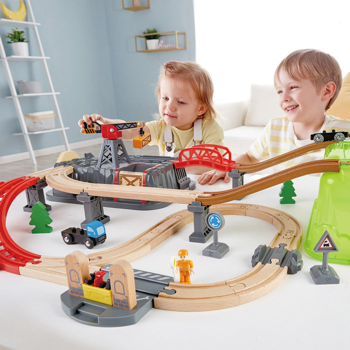 Two children playing with a toy train set in a room.
