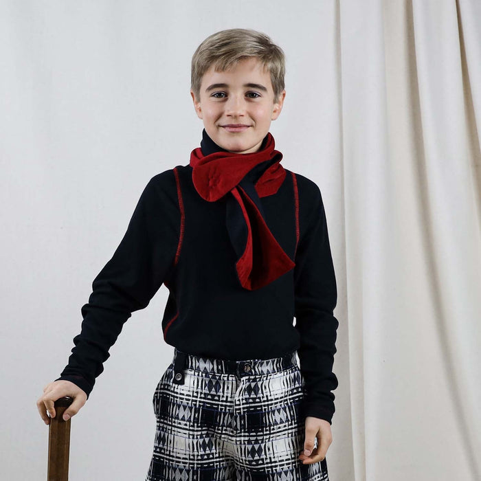 Child wearing a red corduroy scarf wrapped around a coat