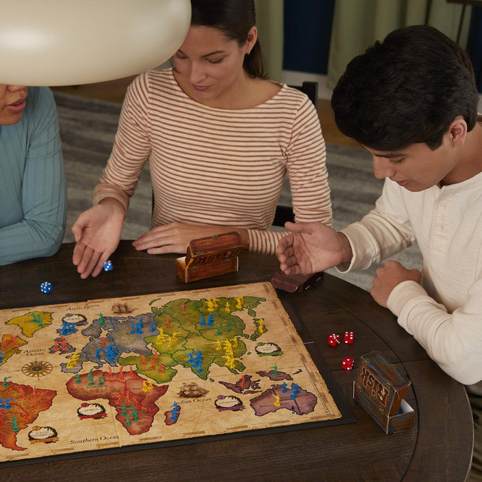 Three people playing Risk on a wooden table.