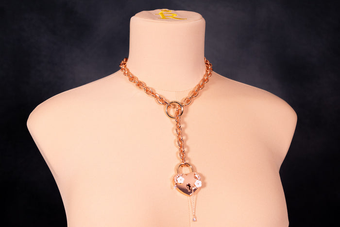 A rose gold deluxe floral lock slip chain collar displayed on a mannequin bust, featuring a sleek heart lock with pearly florals and a dangling crystal.