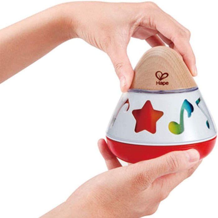 Colorful children's toy with star and music note designs, held by a hand against a white background.