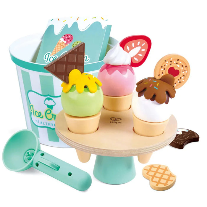 A colorful toy ice cream set including a wooden ice cream stand, a bucket, scoops, and various pretend ice cream cones and toppings.