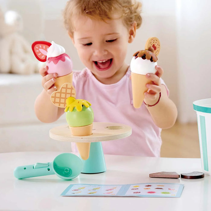 Child playing with toy ice cream cones and a stand on a table.