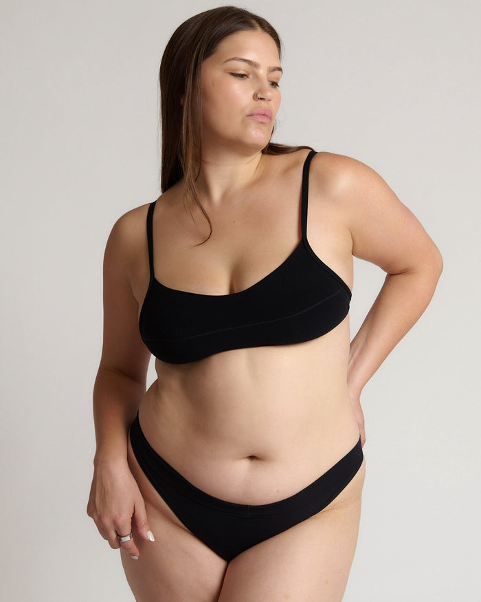 Woman wearing black scoop system against a neutral background
