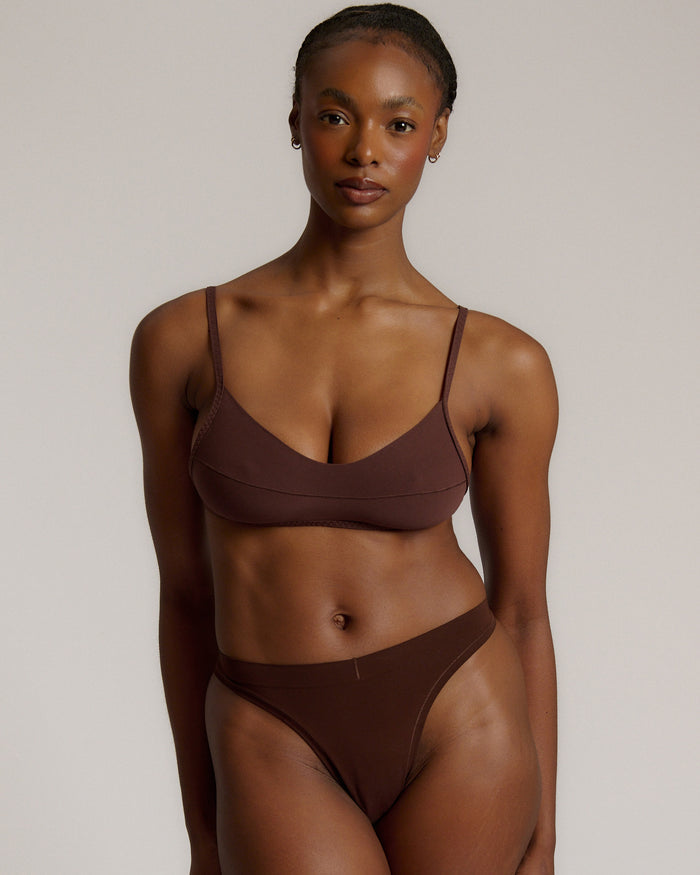 A person wearing a mocha thong and scoop system on a plain background.