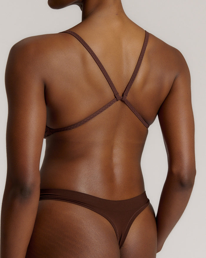 A person wearing a mocha thong and scoop system on a plain background.