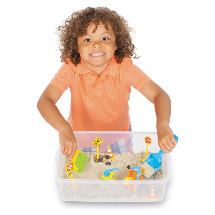 Child playing with a construction sand playset on a white background