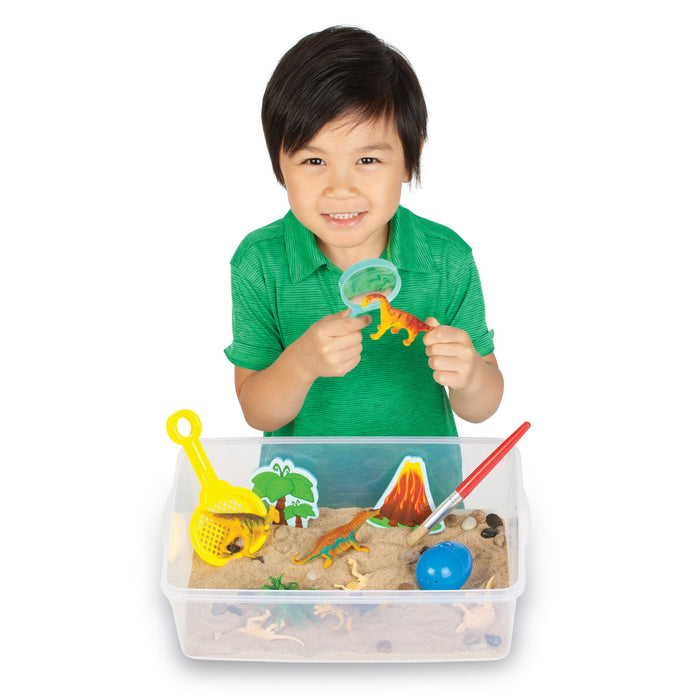 Child playing with a dinosaur sand playset on a white background