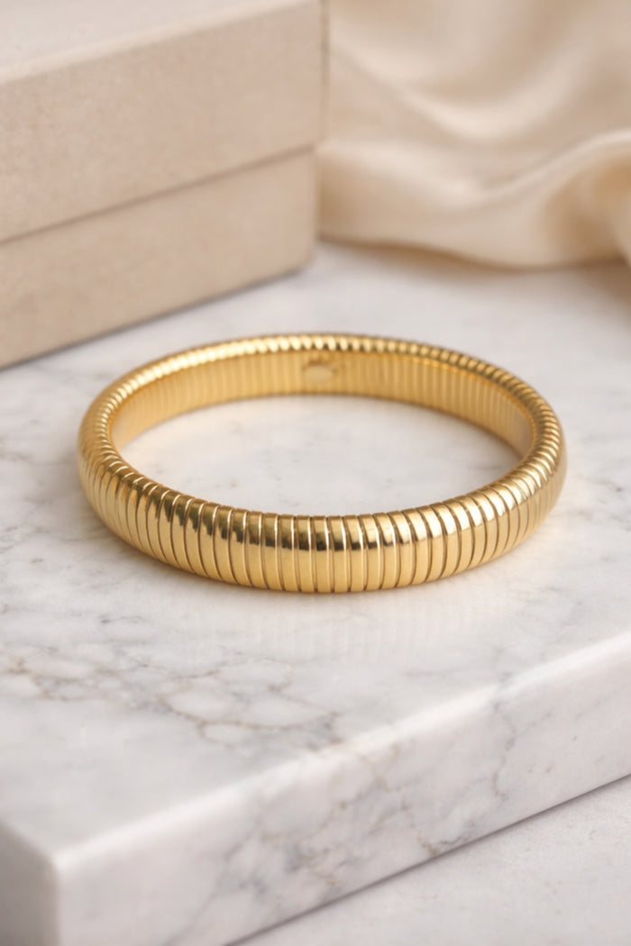 gold snake chain stainless steel bangle bracelet flat lay on marble surface product display