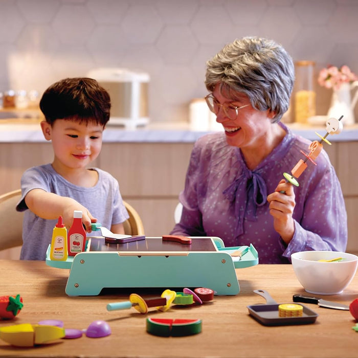Grandmother and grandson playing with toy kitchen set in a kitchen.