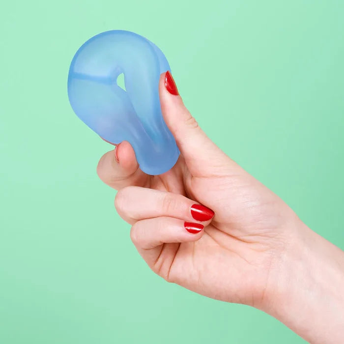 Hand holding a blue silicone product against a green background