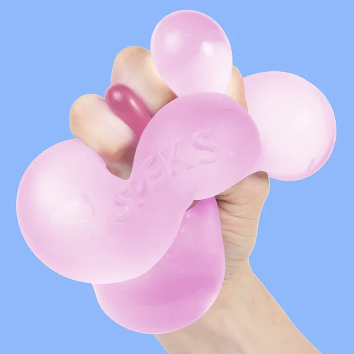 A hand squeezing a pink silicone stress toy with bubble-like shapes and the embossed brand name 'SPEKS' on a solid light blue background.