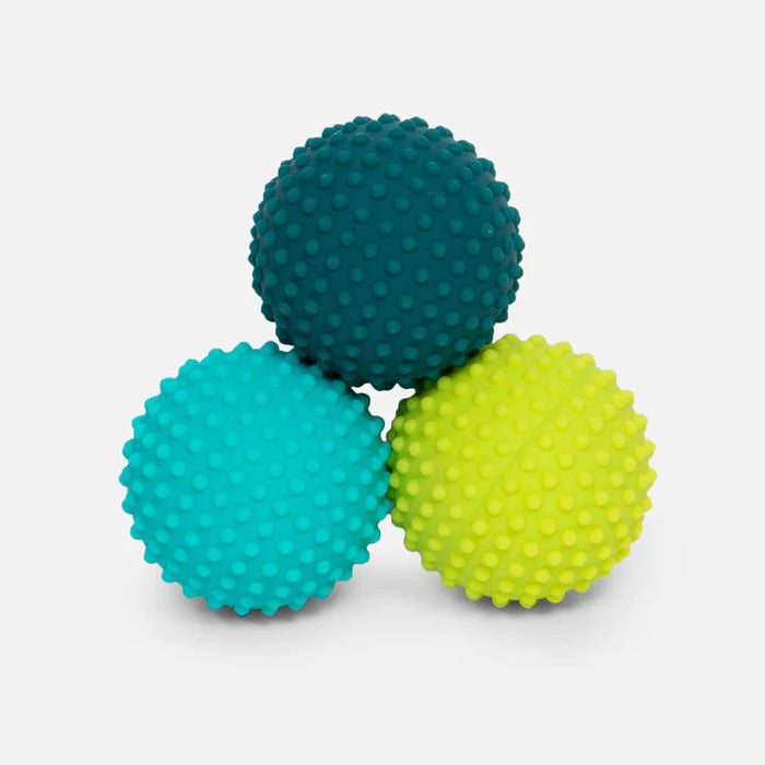 Three textured stress balls in teal, blue, and green on a light gray background