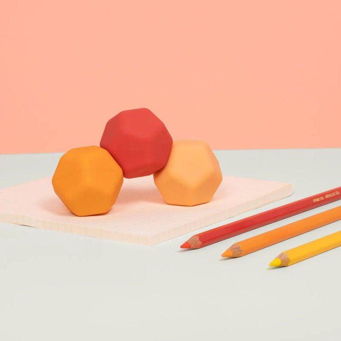 Three colorful Speks Odds on a light surface with two pencils.