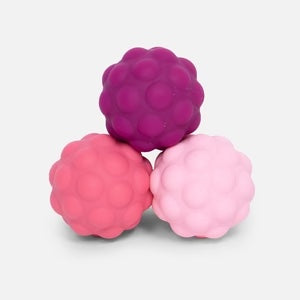 Three textured rubber balls in pink and purple on a light gray background