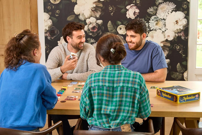People playing Splendor on a wood table with a floral background