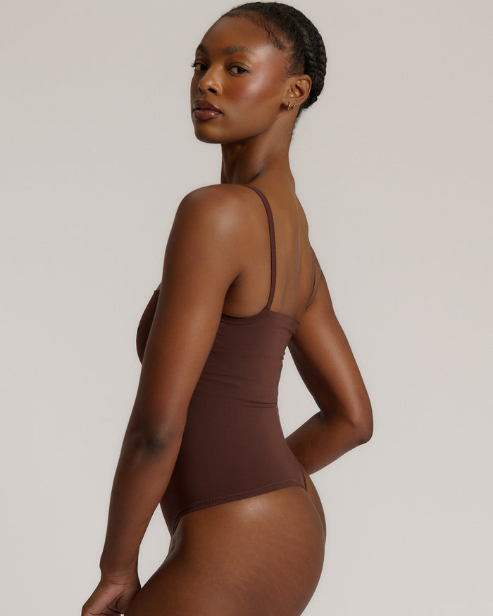 A woman wearing a brown square neck bodysuit with thin straps.