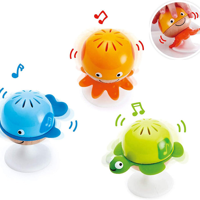 Three colorful bath toys shaped like an octopus, fish, and turtle with musical notes around them on a white background.