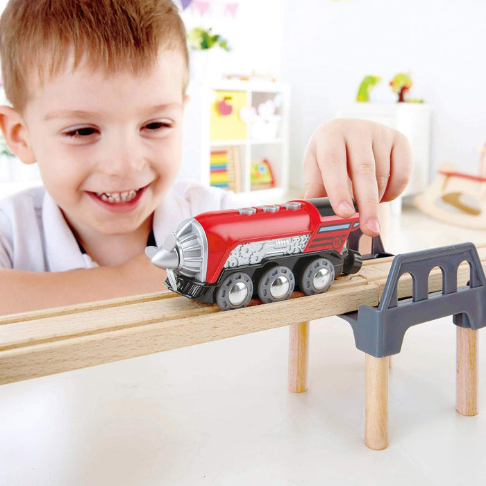 Child playing with a toy train set on a wooden track