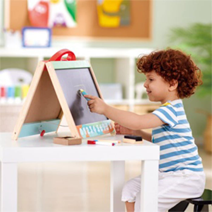 Child seated at a table drawing on the Store and Go Easel