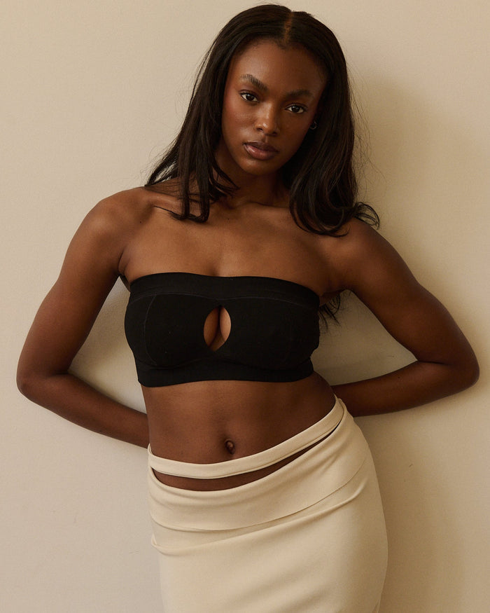 Woman wearing a black strapless system against a plain background