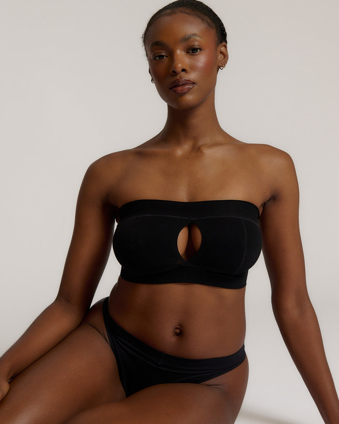 Woman wearing black strapless system against a neutral background