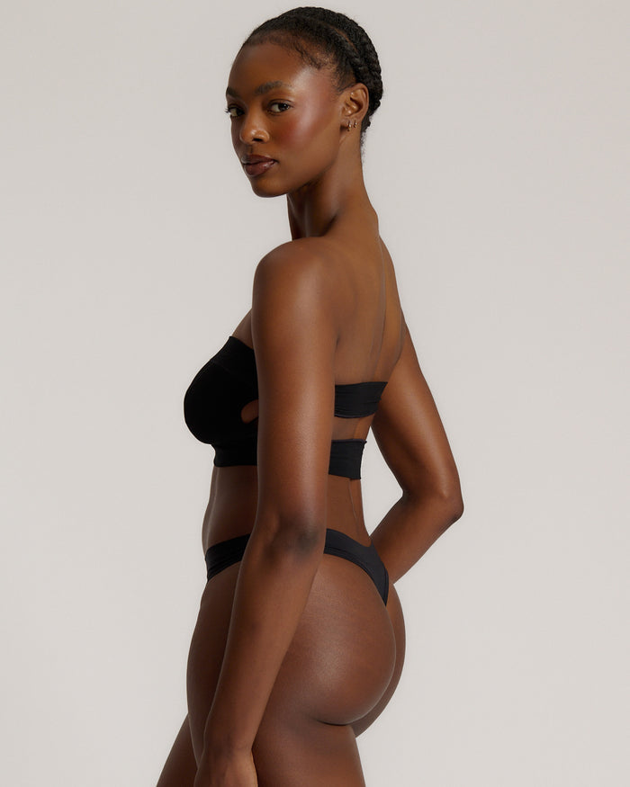 Woman wearing black strapless system against a neutral background