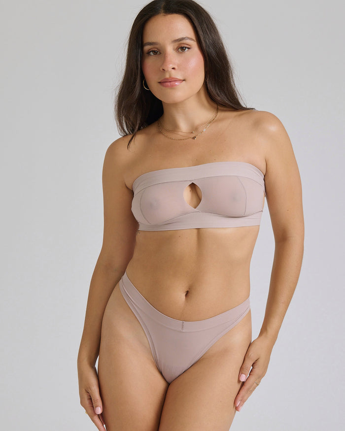Woman wearing a beige strapless against a plain background