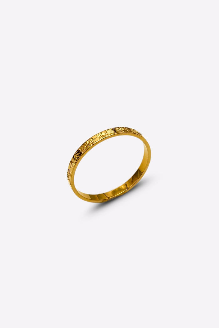 Side perspective of a gold band ring with detailed sun and ray engravings, displayed against a white backdrop.