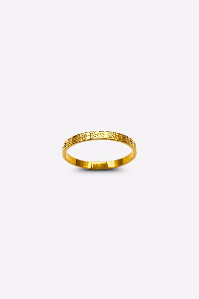Front view of a gold band ring with intricate sun and ray engravings, showcased on a white backdrop.