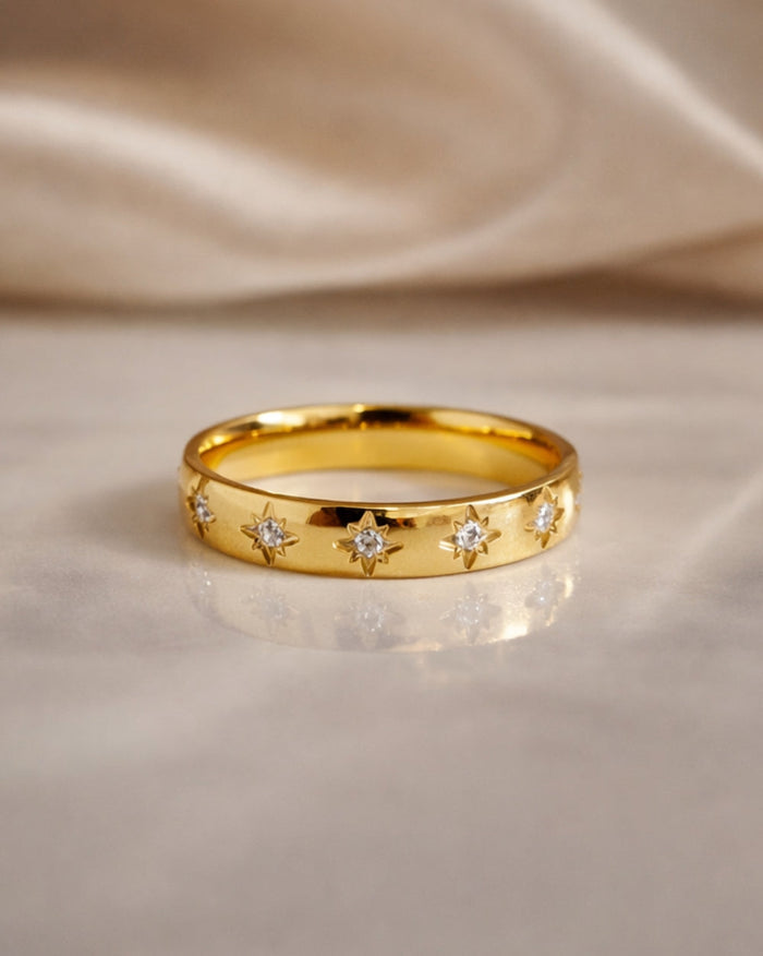 gold gemstone ring polished band sunburst star set stones flat lay marble background